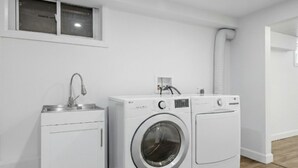 Un cuarto de lavandería con lavadora y pileta.