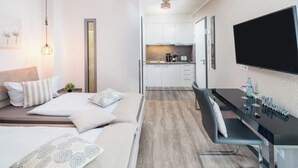 Een moderne hotelkamer met een bed, nachtkastje en een klein kitchenette.