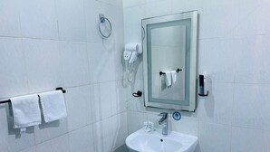 A bathroom with a white sink, a mirror, and a towel rack with two towels. - Doolve Riyadh 1 (Riyadh)