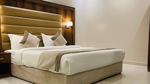 A modern bedroom with a large bed, a wooden headboard, and a nightstand. - Doolve Riyadh 1 (Riyadh)
