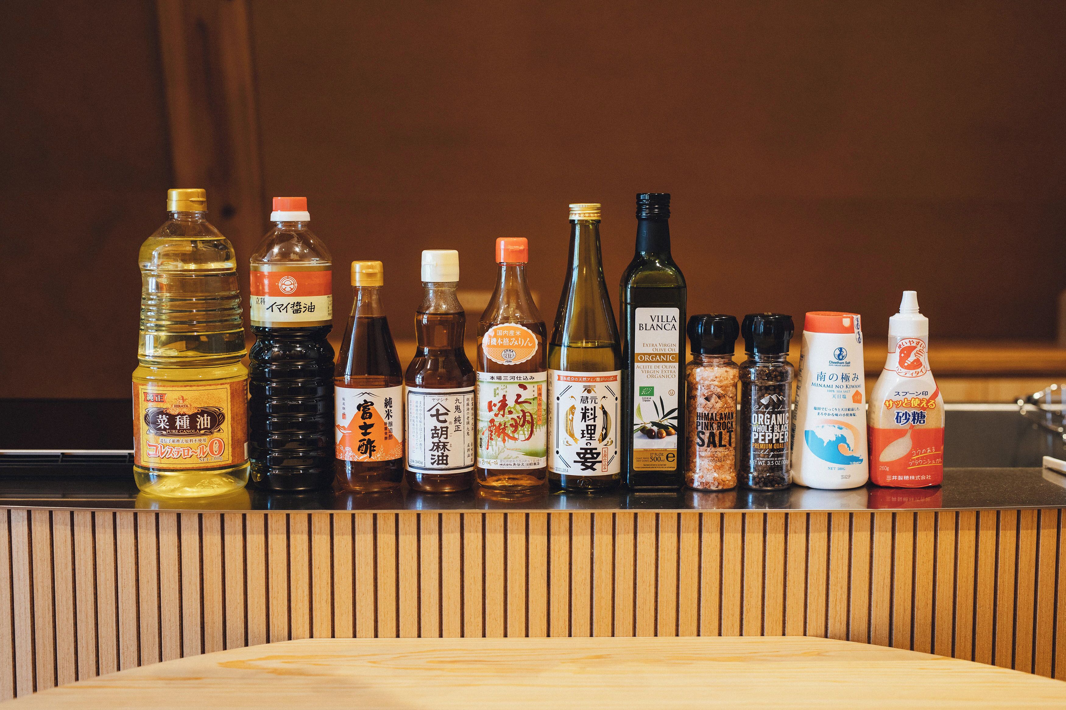 Variedad de botellas de condimentos sobre una encimera de madera.