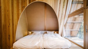 Une chambre à coucher avec un plafond incurvé, des murs en bois et une grande fenêtre.