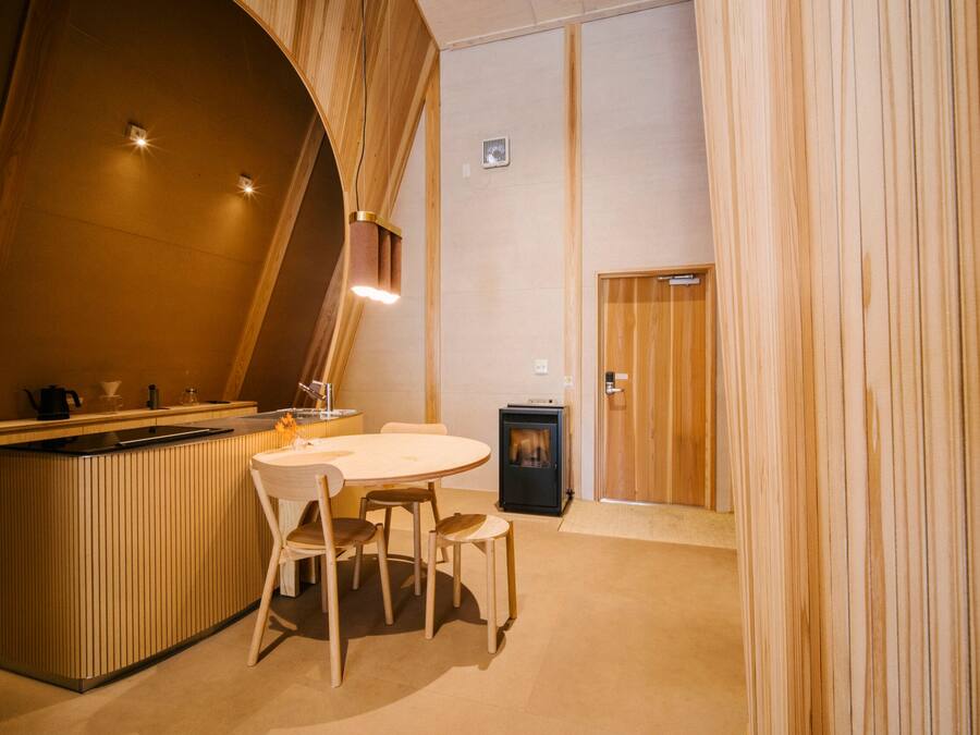 A cozy, modern kitchen with a wooden island, a round dining table, and chairs. There is a small stove and a cabinet with a microwave.