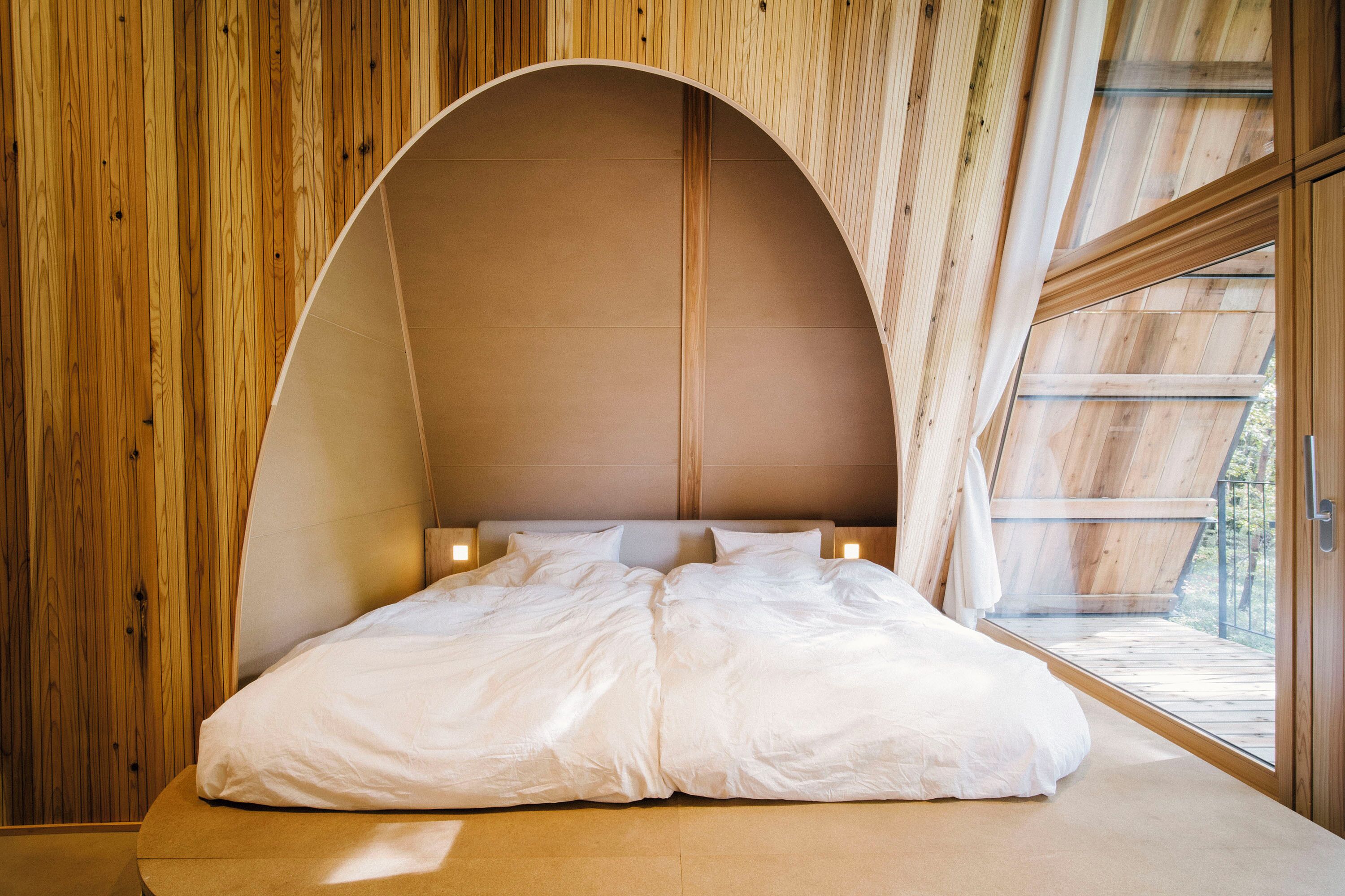 Une chambre avec un plafond incurvé, des murs en bois et une grande fenêtre.
