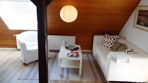 A room with a white sofa, a small white table, a hanging light fixture, and a wooden ceiling. - Holiday Apartment 'Ferienwohnung Rathjen' with Private Terrace, Shared Garden and Wi-Fi (Cuxhaven)