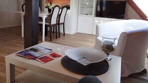 A modern room with a dining area, a TV, and a glass table with a wine glass. - Holiday Apartment 'Ferienwohnung Rathjen' with Private Terrace, Shared Garden and Wi-Fi (Cuxhaven)