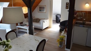 A modern interior with a dining table, chairs, a sofa, a kitchen area, and a staircase. - Holiday Apartment 'Ferienwohnung Rathjen' with Private Terrace, Shared Garden and Wi-Fi (Cuxhaven)