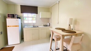 A compact kitchen with a refrigerator, microwave, sink, and a small dining table with chairs. - Cozy & Central Stay in Curaçao (Willemstad)