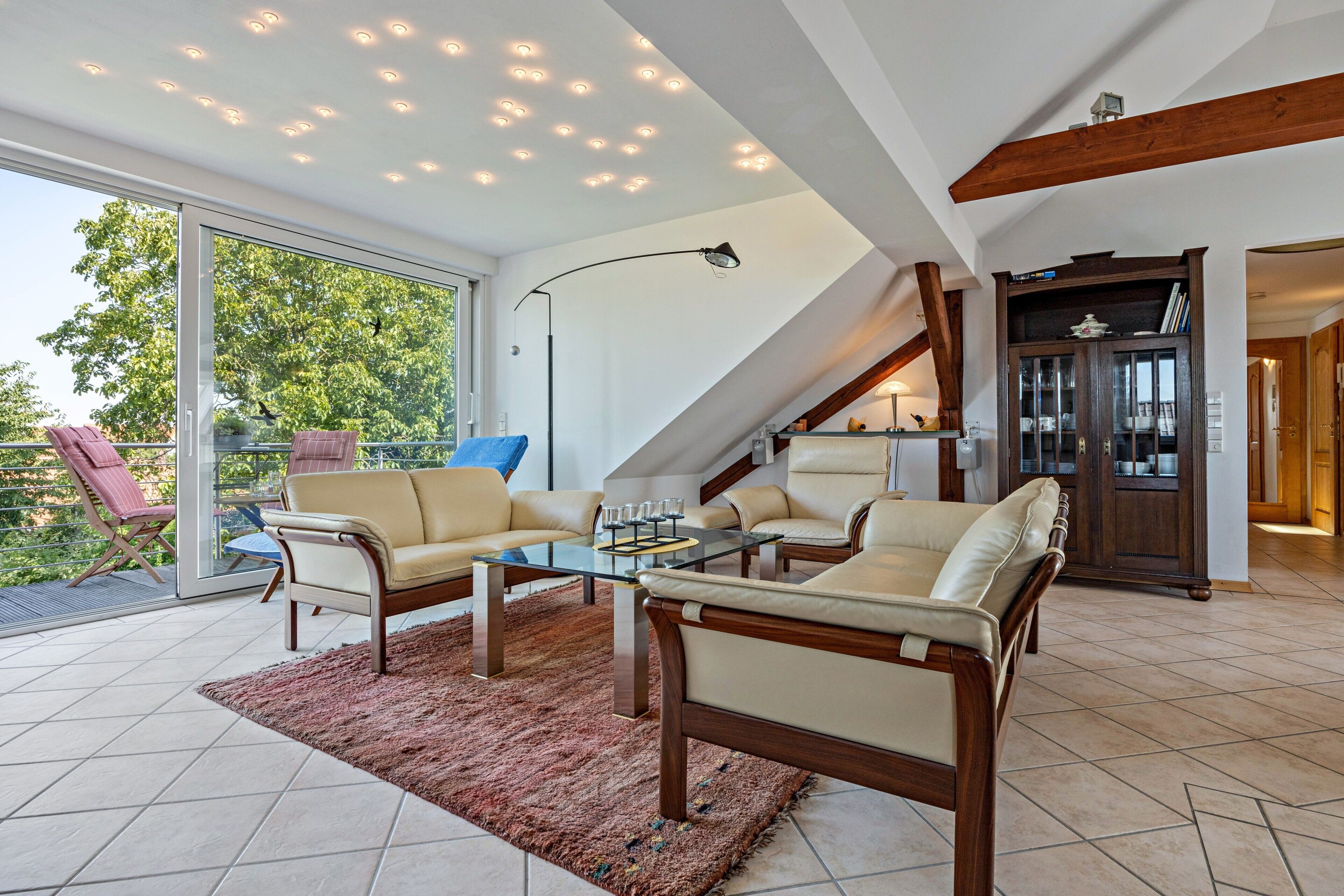 A modern living room with a glass coffee table, leather sofas, and a staircase leading to an upper level.