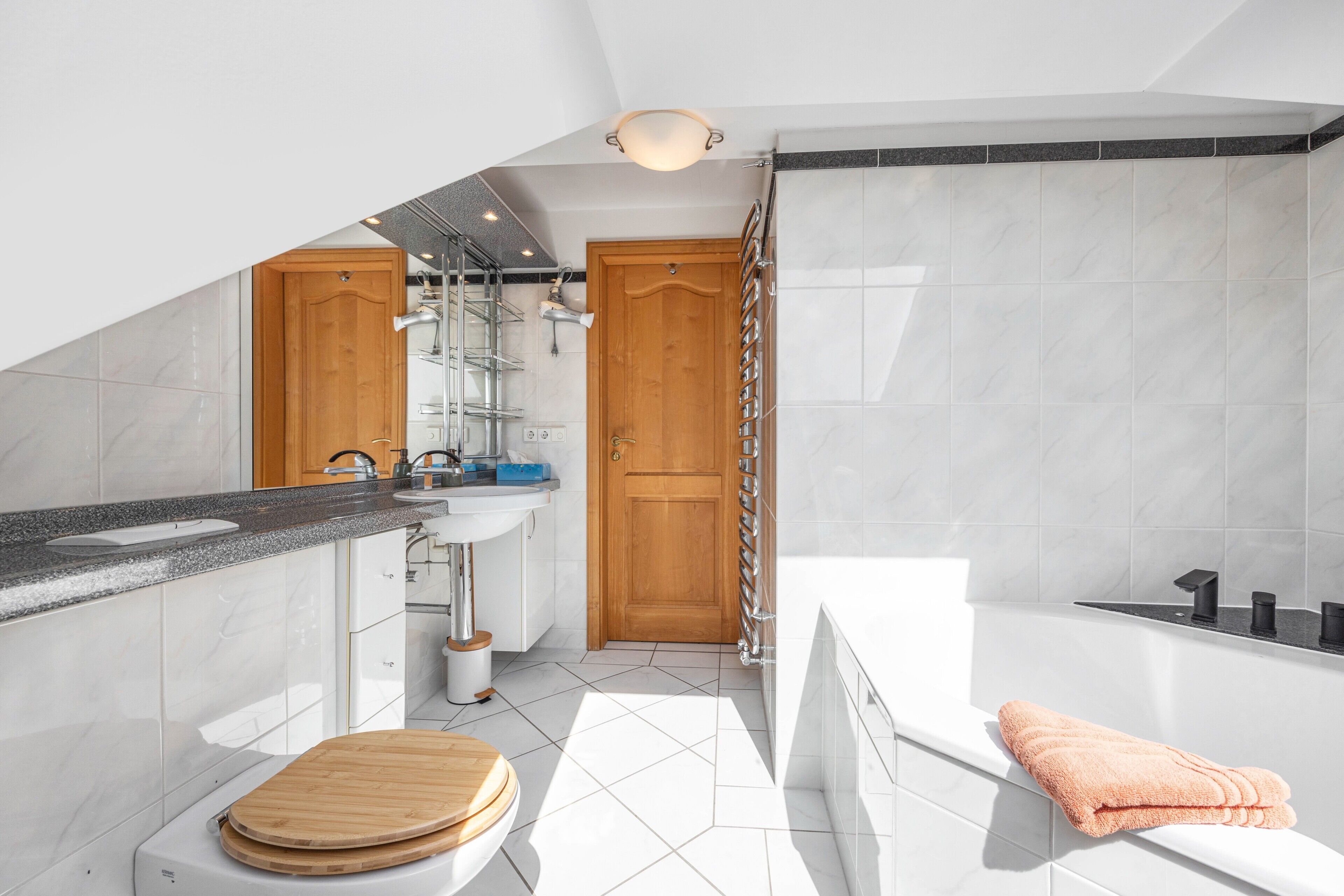 A modern bathroom with a bathtub, a wooden door, and a sink.