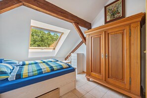 A bedroom with a skylight, a bed with a blue mattress, a wooden wardrobe, and a white radiator. - Apartment 'Dachstübchen' with Balcony (Hagenburg)