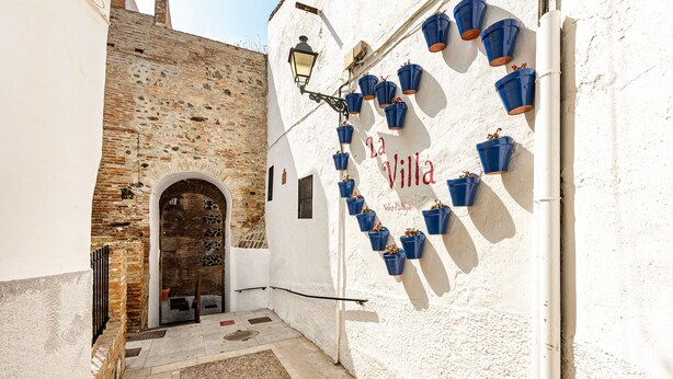 A narrow alleyway with a white wall, a wooden door, and blue flower pots arranged in a heart shape. - Chalet 'Casa Limón' with Mountain View, Wi-Fi and Air Conditioning (Vélez-Málaga)