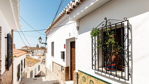 A narrow street with white buildings, a tiled roof, and a window with a plant. - Chalet 'Casa Limón' with Mountain View, Wi-Fi and Air Conditioning (Vélez-Málaga)