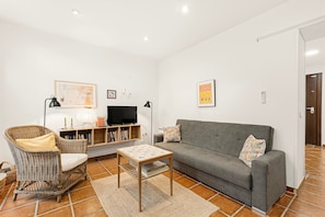 A living room with a grey sofa, wicker armchair, small table, and a television. - Chalet 'Casa Limón' with Mountain View, Wi-Fi and Air Conditioning (Vélez-Málaga)