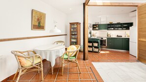 A dining area with wicker chairs, a round table, and a painting on the wall. - Chalet 'Casa Limón' with Mountain View, Wi-Fi and Air Conditioning (Vélez-Málaga)