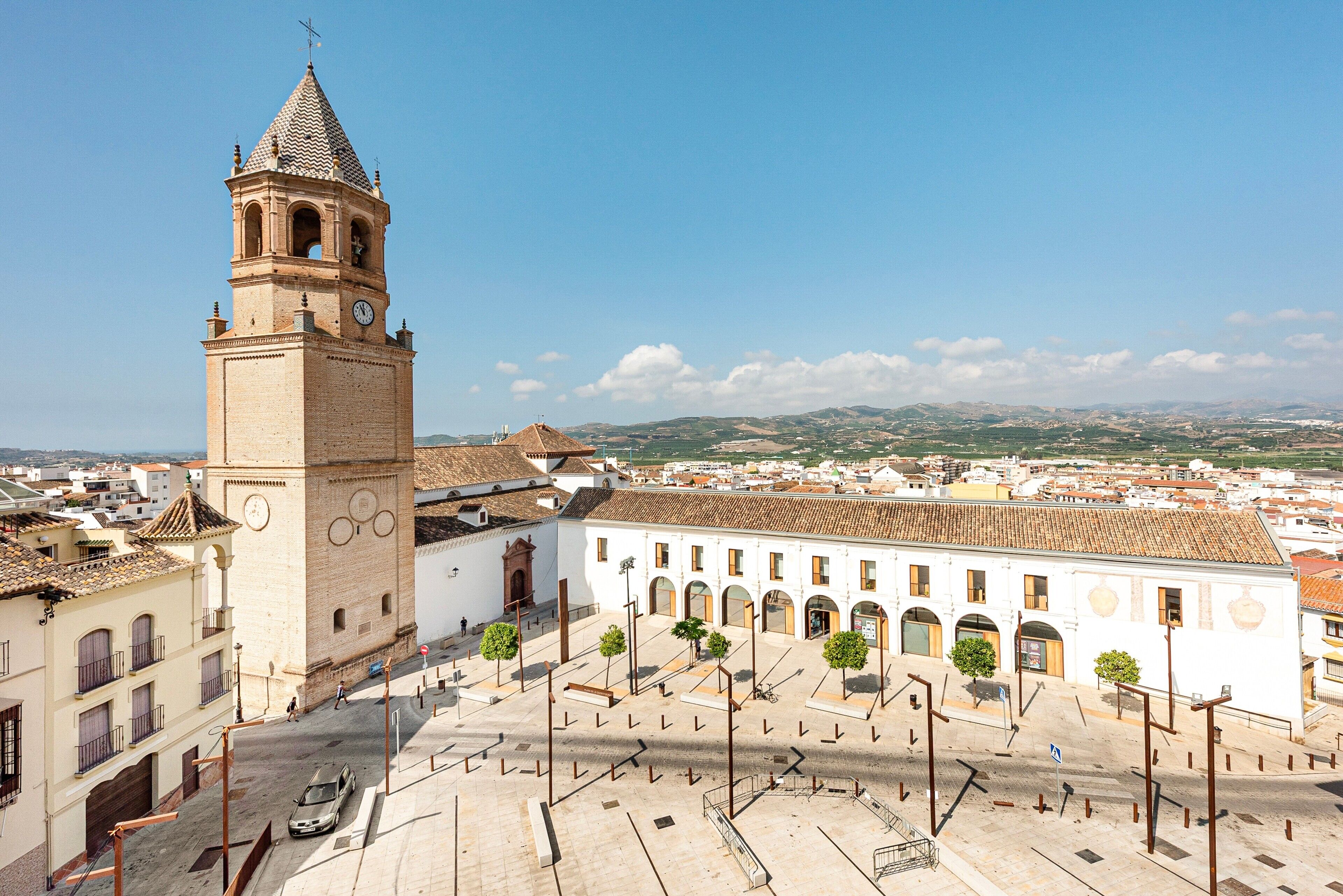 A historic building with a clock tower, a courtyard with trees, and a view of the surrounding cityscape.