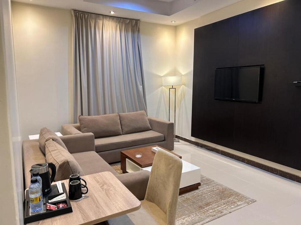 A modern living room with a sofa, coffee table, and a flat-screen TV mounted on the wall.