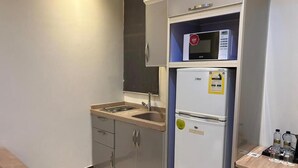 Una cocina compacta con microondas, refrigerador y lavamanos.
