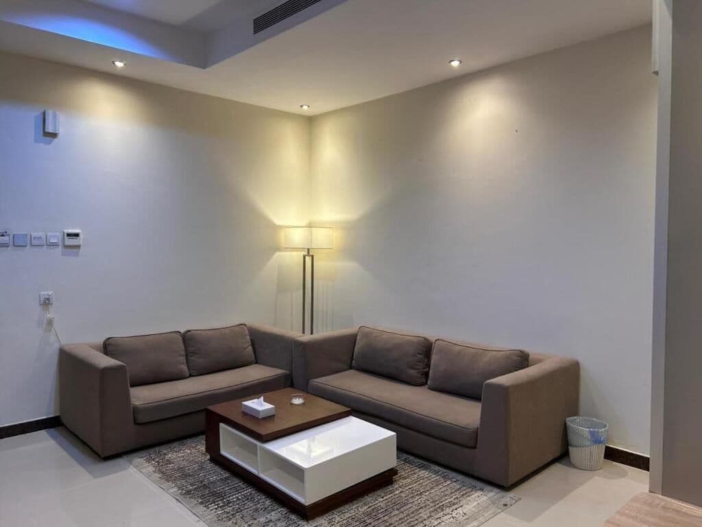 A modern living room with two sofas, a coffee table, a floor lamp, and a trash bin.