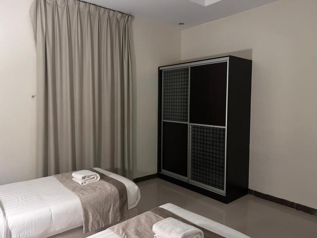 A hotel room with a bed, a wardrobe, and a window with curtains.