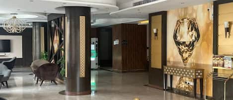 A modern lobby with a reception desk, seating area, and a decorative wall.