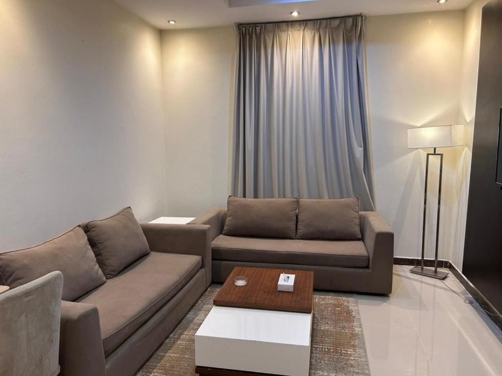 A modern living room with a sofa, a coffee table, and a lamp.