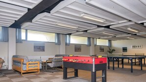 Een kamer met een tafelvoetbaltafel, een bank en een pingpongtafel.