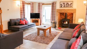 A cozy living room with a fireplace, a sofa, a TV, and a coffee table. - The Barn (Matlock)