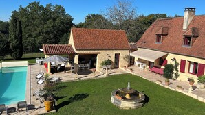A house with a swimming pool, outdoor seating, and a fountain. - Gîte du pigeonnier with swimming pool Périgord noir Les hirondelles 5 persons (Saint-Félix-de-Reillac-et-Mortemart)
