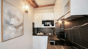 A compact kitchen with white cabinets, a black countertop, a microwave, and a dishwasher. - 841 Polytech (Paris)