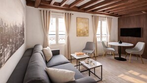 A modern living room with a sofa, two chairs, a coffee table, and a TV. - 841 Polytech (Paris)