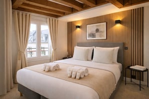 A hotel room with a large bed, a bedside table, a window with curtains, and a wall-mounted light. - 841 Polytech (Paris)