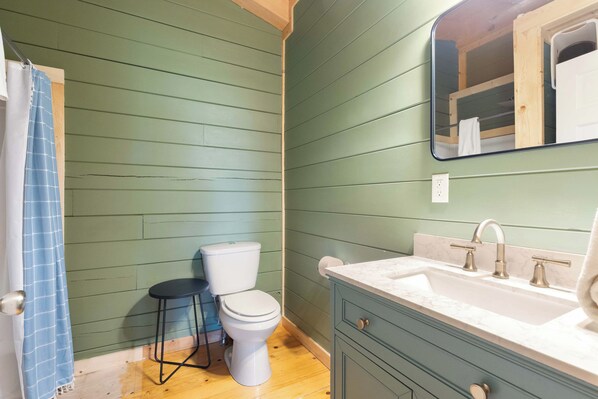 A bathroom with a toilet, sink, and mirror.