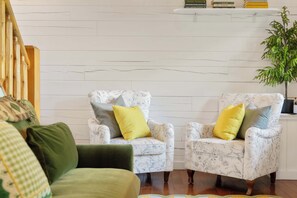 A room with two armchairs, a sofa, and a bookshelf against a white wall. - Romantic Cabin: Hot Tub•Outdoor Movies•Fireplace (Logan)