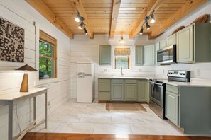 A kitchen with white cabinets, a refrigerator, a microwave, and an oven. - Romantic Cabin: Hot Tub•Outdoor Movies•Fireplace (Logan)