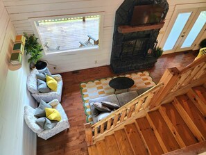 A cozy living area with a sofa, a small table, a fireplace, and a view through a window.