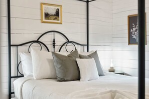 A bed with a metal frame, white bedding, and multiple pillows. - Romantic Cabin: Hot Tub•Outdoor Movies•Fireplace (Logan)