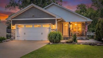 Ein zweigeschossiges Haus mit Garage, einer Veranda mit Steinuntergrund und einem gepflegten Rasen.