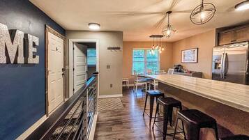 A modern kitchen with a bar area, wooden flooring, and a view to the dining area.