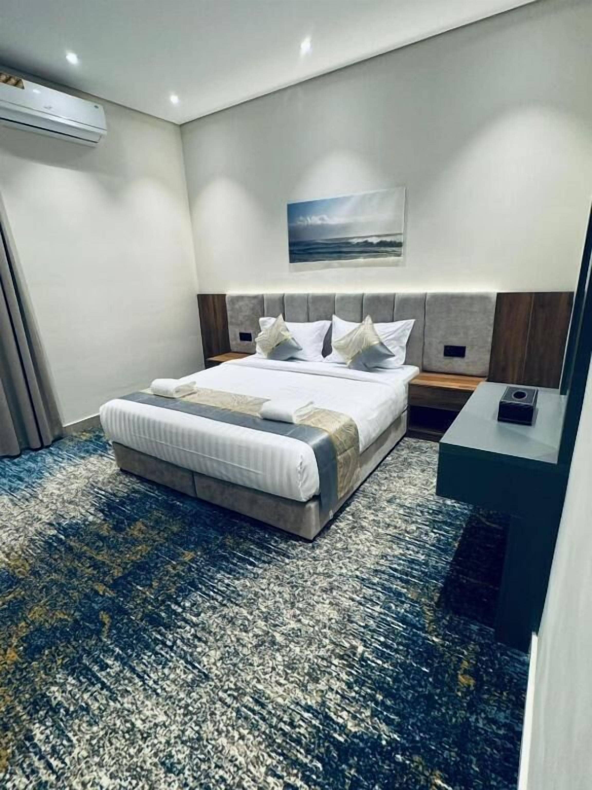 Ein Hotelzimmer mit einem großen Bett, einem Bettkasten, einem Nachttisch und einer wandmontierten Klimaanlage.