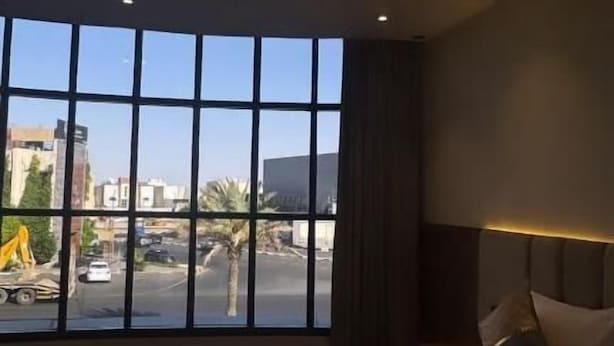 A hotel room with a large window, a bed, and a nightstand.