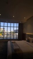 Una habitación de hotel con un ventanal grande, una cama y una mesita de noche.