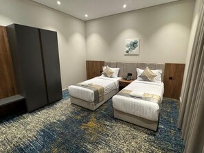 A hotel room with two beds, a wardrobe, a wall-mounted artwork, and a carpeted floor.