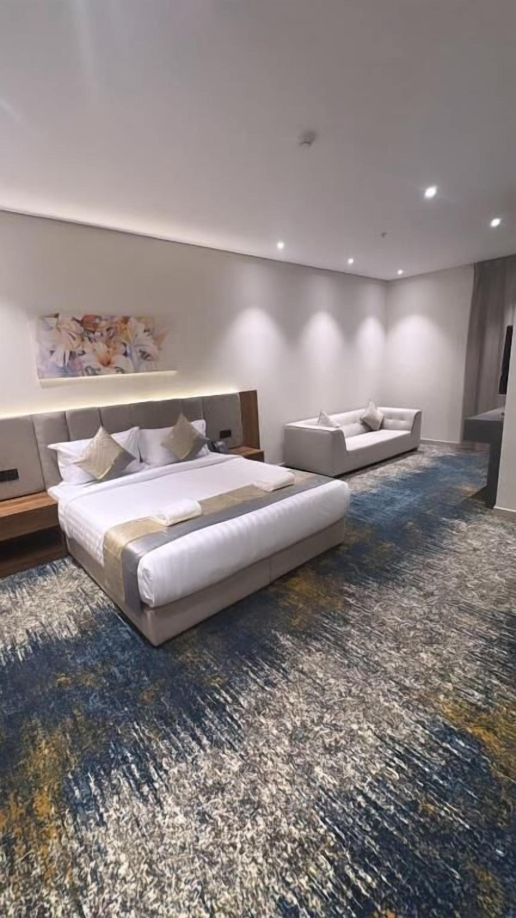Et moderne hotelværelse med en stor seng, en sofa, et skrivebord og et fladskærms-TV.