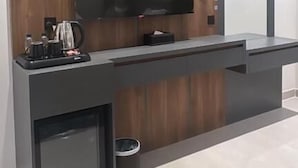 A modern kitchen with a built-in TV, a coffee machine, and a small refrigerator.