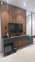 Una cocina moderna con televisión integrada, una cafetera y un refrigerador pequeño.