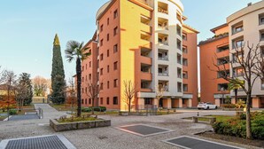 A multi-story residential building with balconies, a central courtyard, and a palm tree. - [10min BGY Airport] Bilo Chic: garage + A/C (Seriate)