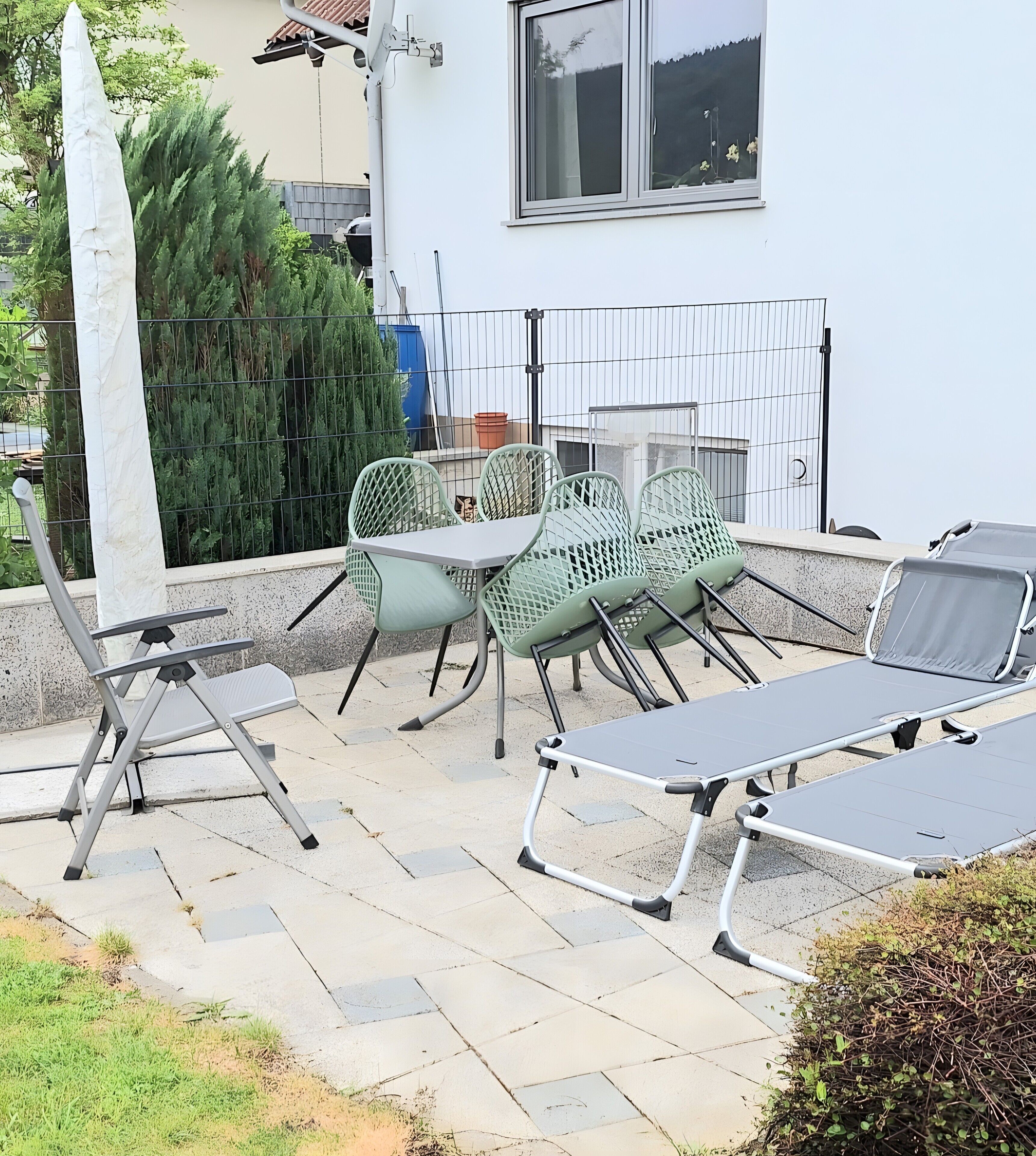 En uteplats med utemöbler, inklusive ett bord och stolar, samt ett solskydd.