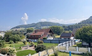 A residential area with houses, a garden with a fountain, and a hilly landscape in the background. - Apartment 'Pure Vista' with Black Forest View, Private Terrace and Wi-Fi (Laufenburg)