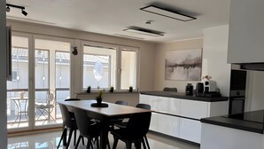 A modern kitchen with a dining area, large windows, and a flat-screen TV. - Apartment 'Pure Vista' with Black Forest View, Private Terrace and Wi-Fi (Laufenburg)